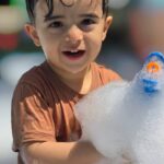 کودک ۵ ساله در حال خندیدن بین کف‌های فستیوال آبی
